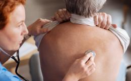 Pielęgniarka osłuchuje plecy badanego mężczyzny